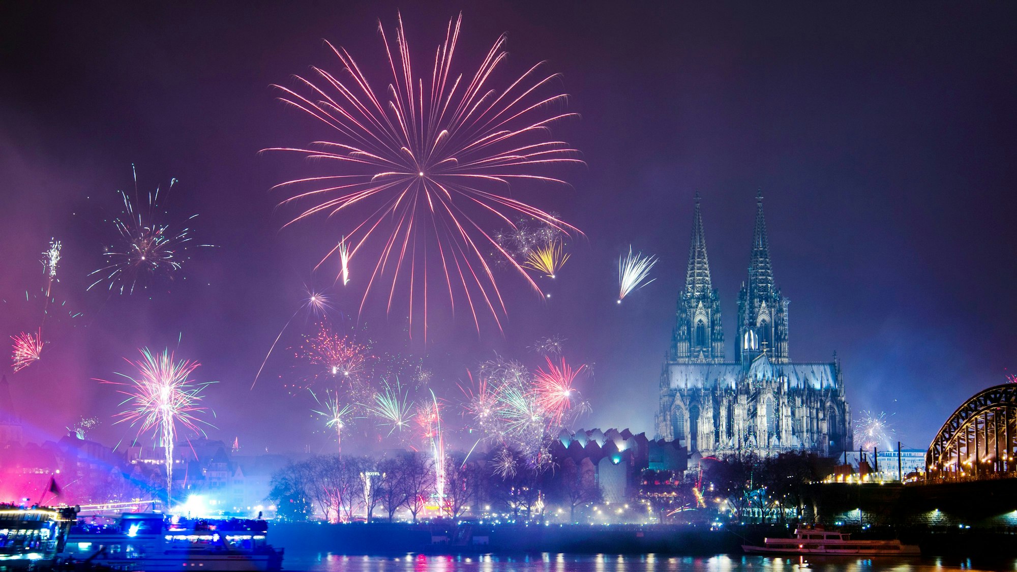 Feuerwerk ist in der Silvesternacht am Rhein über dem Dom zu sehen.