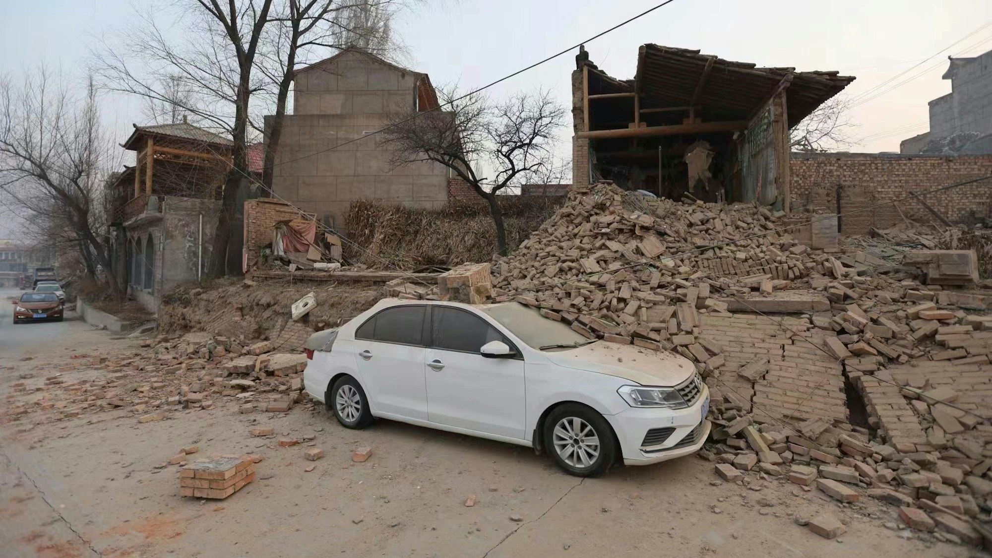 Erdbeben in China: Ein Fahrzeug wird nach einem Erdbeben im Dorf Dahejia in der nordwestchinesischen Provinz Gansu teilweise von einem eingestürzten Gebäude abgedeckt.