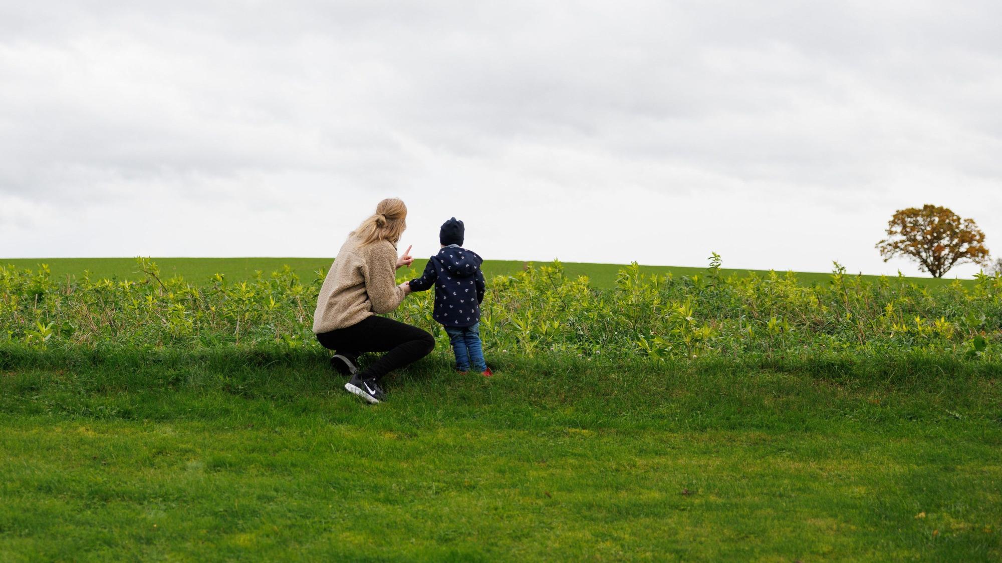 Julia Trienens blickt mit ihrem Kind auf eine Wiese in der Umgebung ihres Wohnhauses.