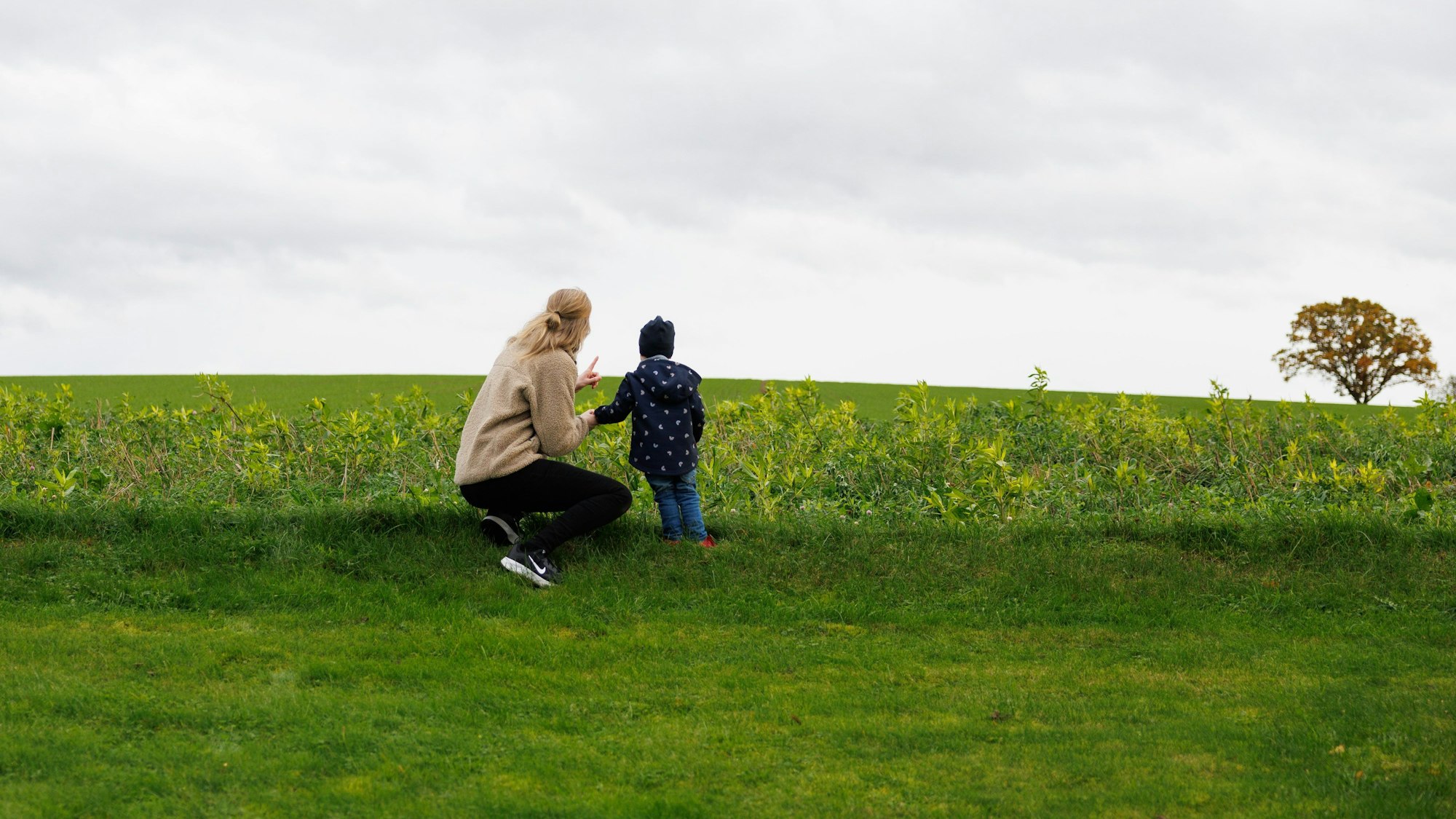 Julia Trienens blickt mit ihrem Kind auf eine Wiese in der Umgebung ihres Wohnhauses.
