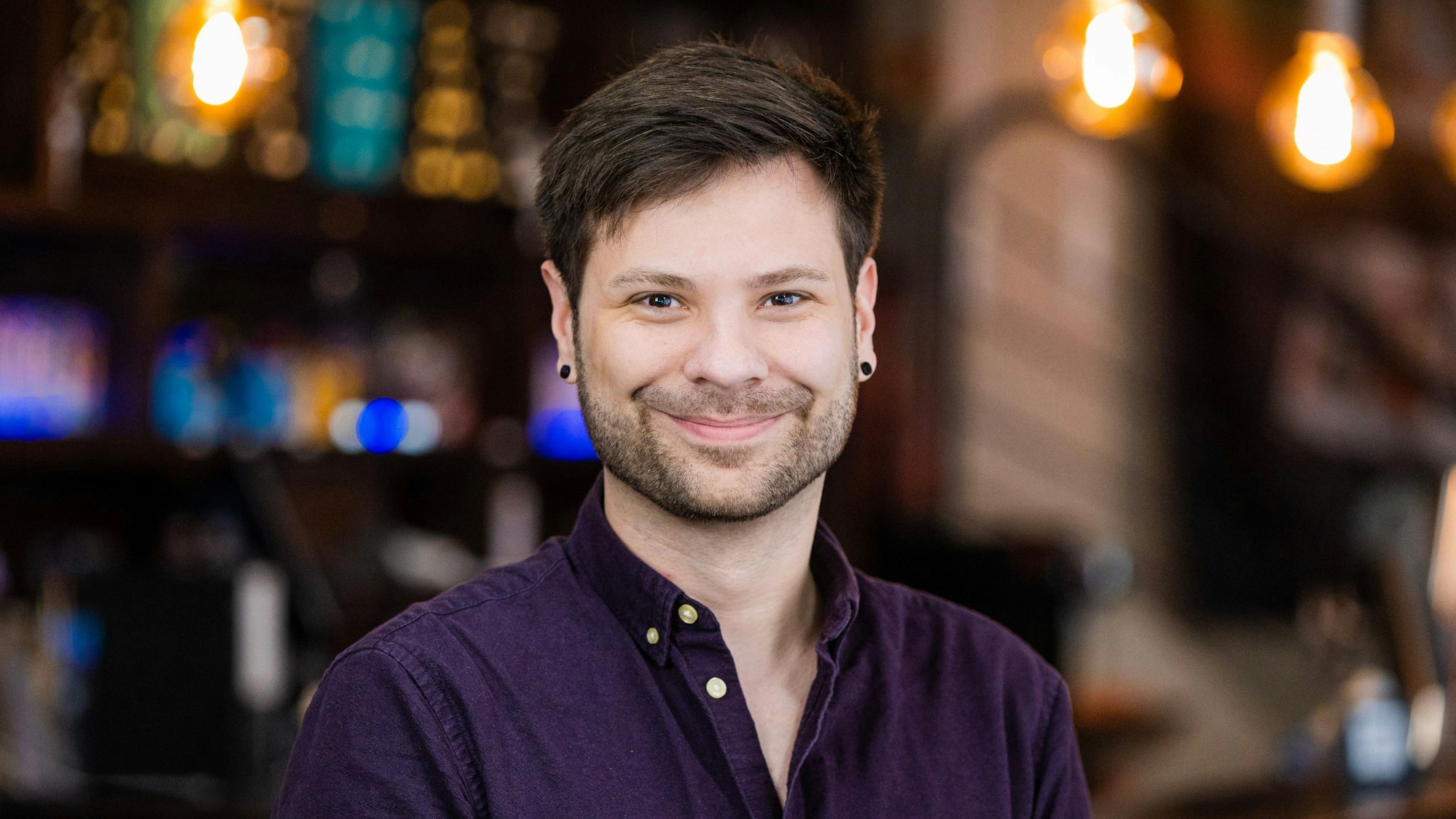 Dominik Weiss ist „WiR*“-Projektleiter beim anyway Köln, er trägt einen braunen Bart, braune Haare und zwei schwarze Ohrringe