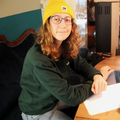 Lisa Stangenberg sitzt an einem Tisch, mit Kamera, Laptop und Film-Skript.