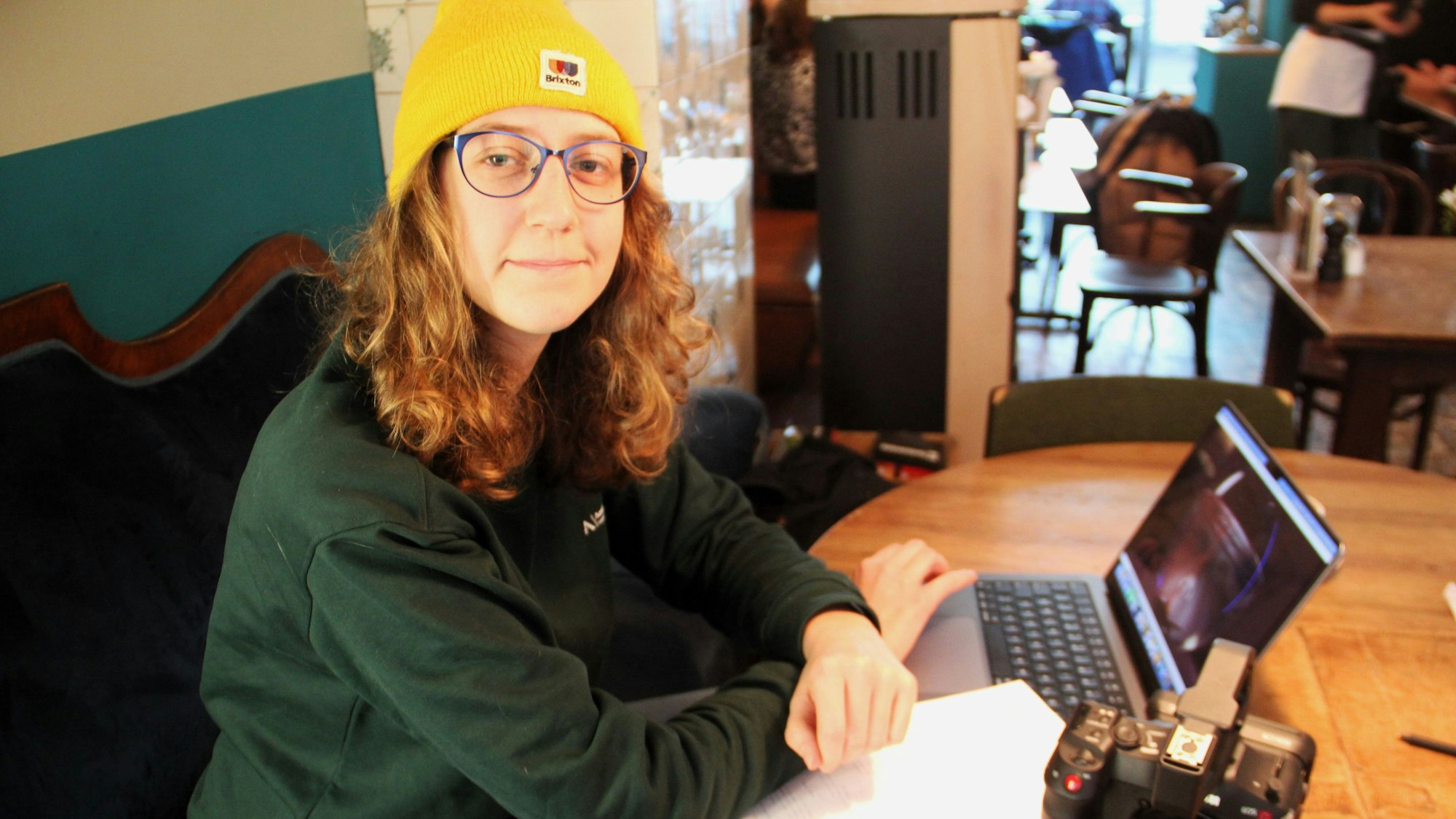 Lisa Stangenberg sitzt an einem Tisch, mit Kamera, Laptop und Film-Skript.