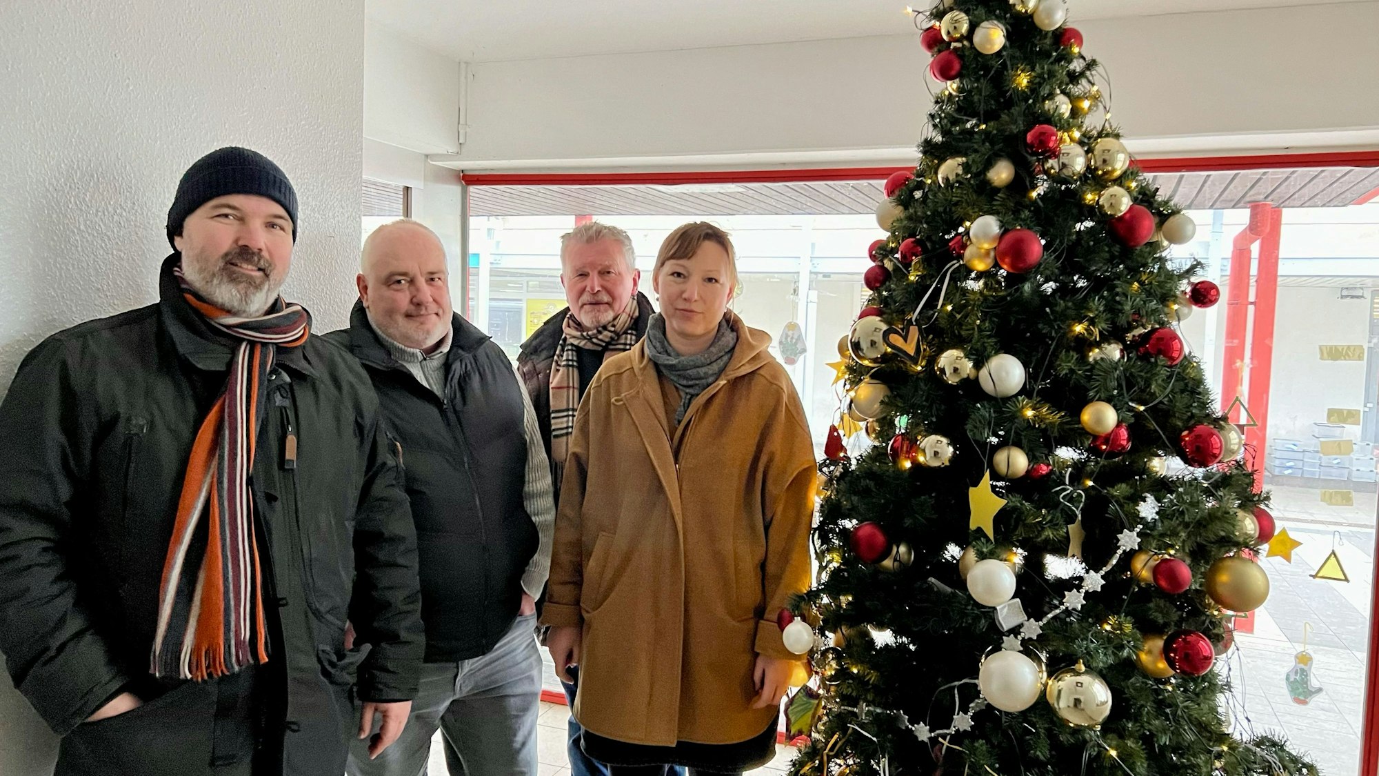 Vier Leute stehen an einem Weihnachtsbaum.