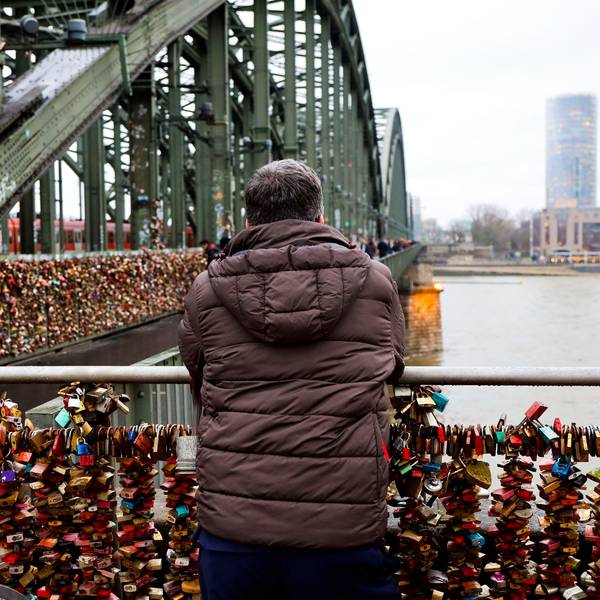 Ein Mann steht auf der Hohenzollernbrücke und blickt auf den Rhein