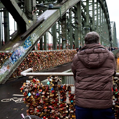 Ein Mann steht auf der Hohenzollernbrücke und blickt auf den Rhein