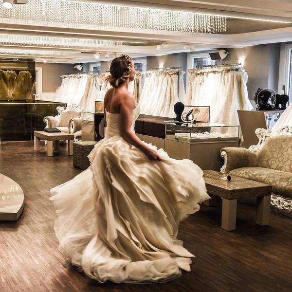 Eine Frau im Brautkleid steht in einem Brautmode-Laden und dreht sich.