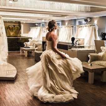 Eine Frau im Brautkleid steht in einem Brautmode-Laden und dreht sich.