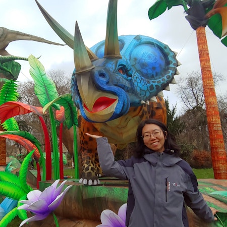 Frau vor einer großen Dinosaurier-Statue