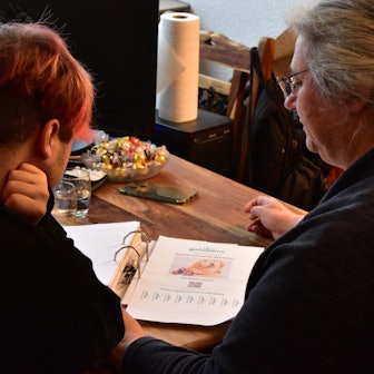 Mutter und Sohn sitzen am Tisch und gucken Unterlagen durch.