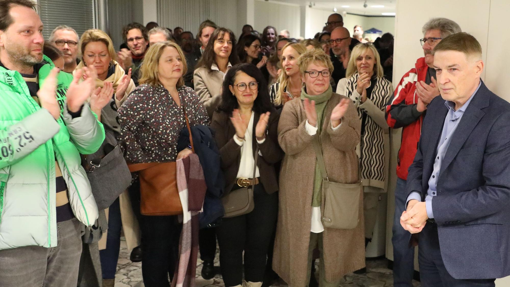 Kreisdirektor Dr. Erik Werdel steht im Foyer des Kreishauses, Menschen klatschen für ihn.