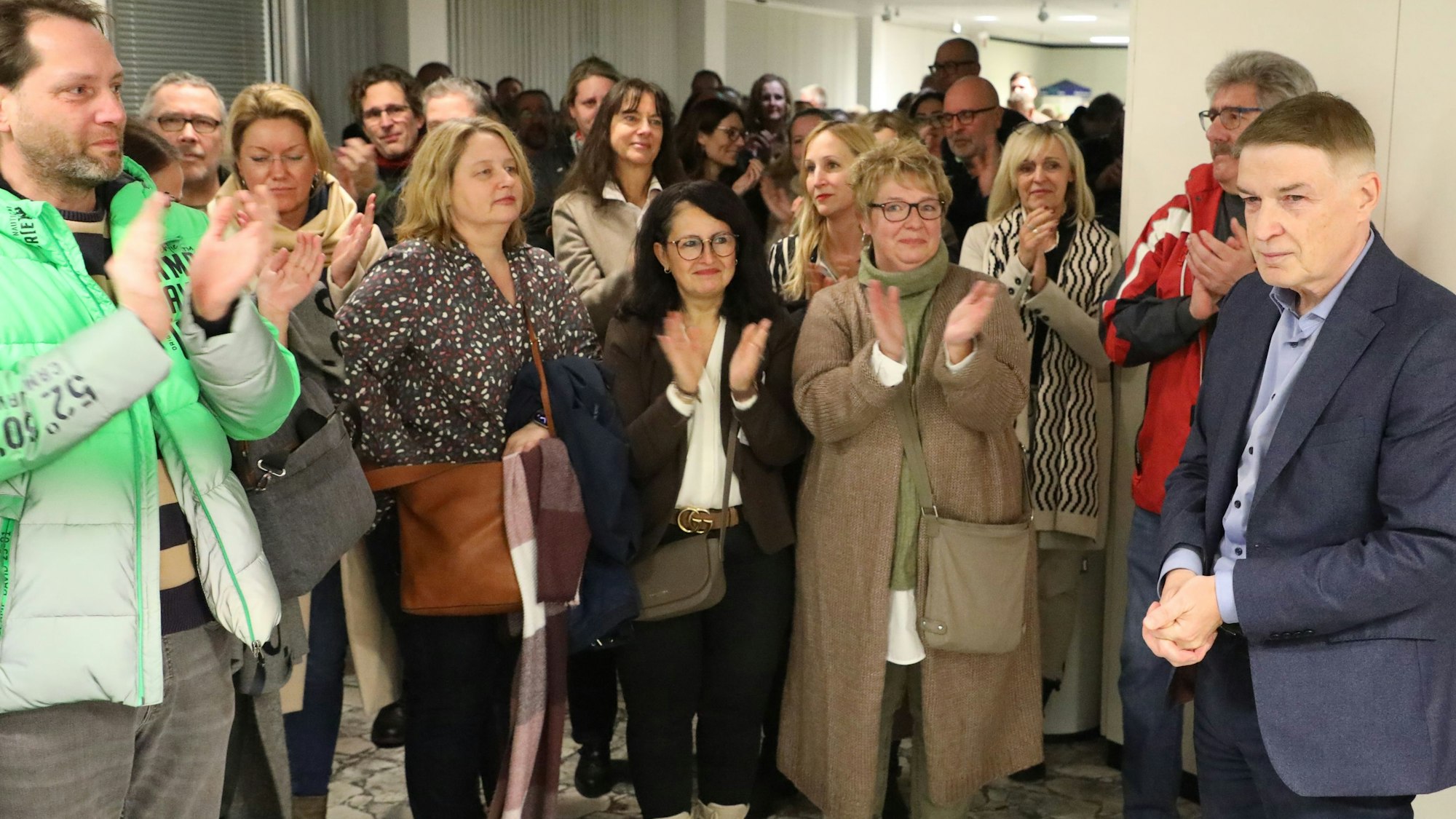 Kreisdirektor Dr. Erik Werdel steht im Foyer des Kreishauses, Menschen klatschen für ihn.