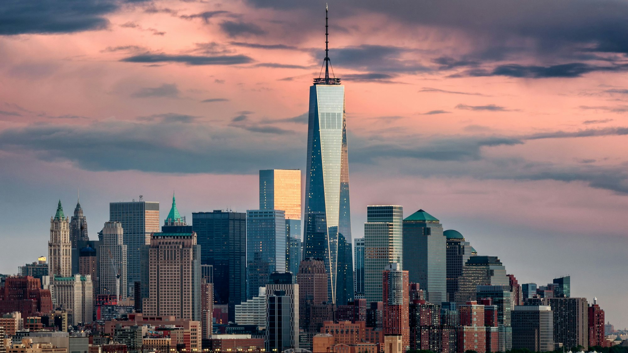 Lower Manhattan und das One World Trade Center in New York City, aufgenommen bei Sonnenuntergang von Weehawken, New Jersey.