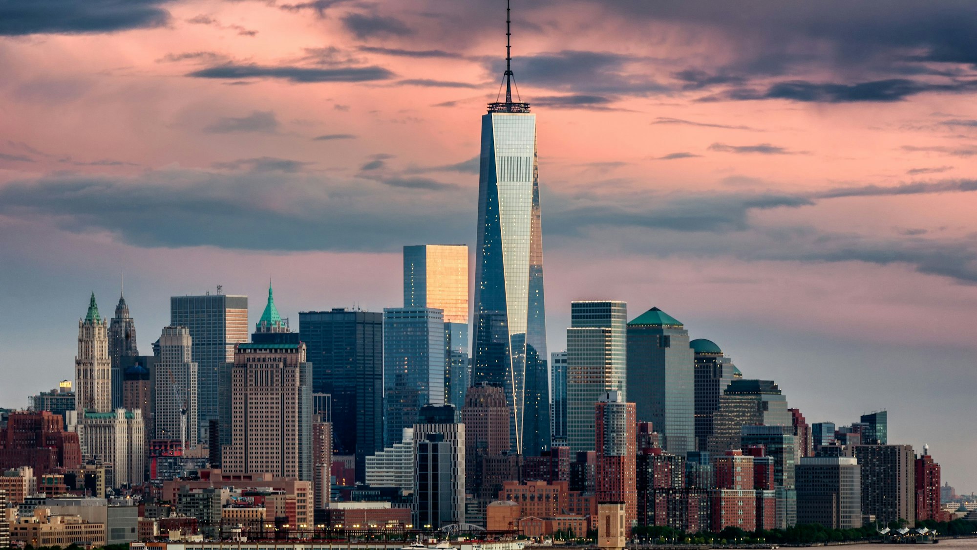 Lower Manhattan und One World Trade Center in New York City, von Weehawken, New Jersey aus gesehen, aufgenommen bei Sonnenuntergang.