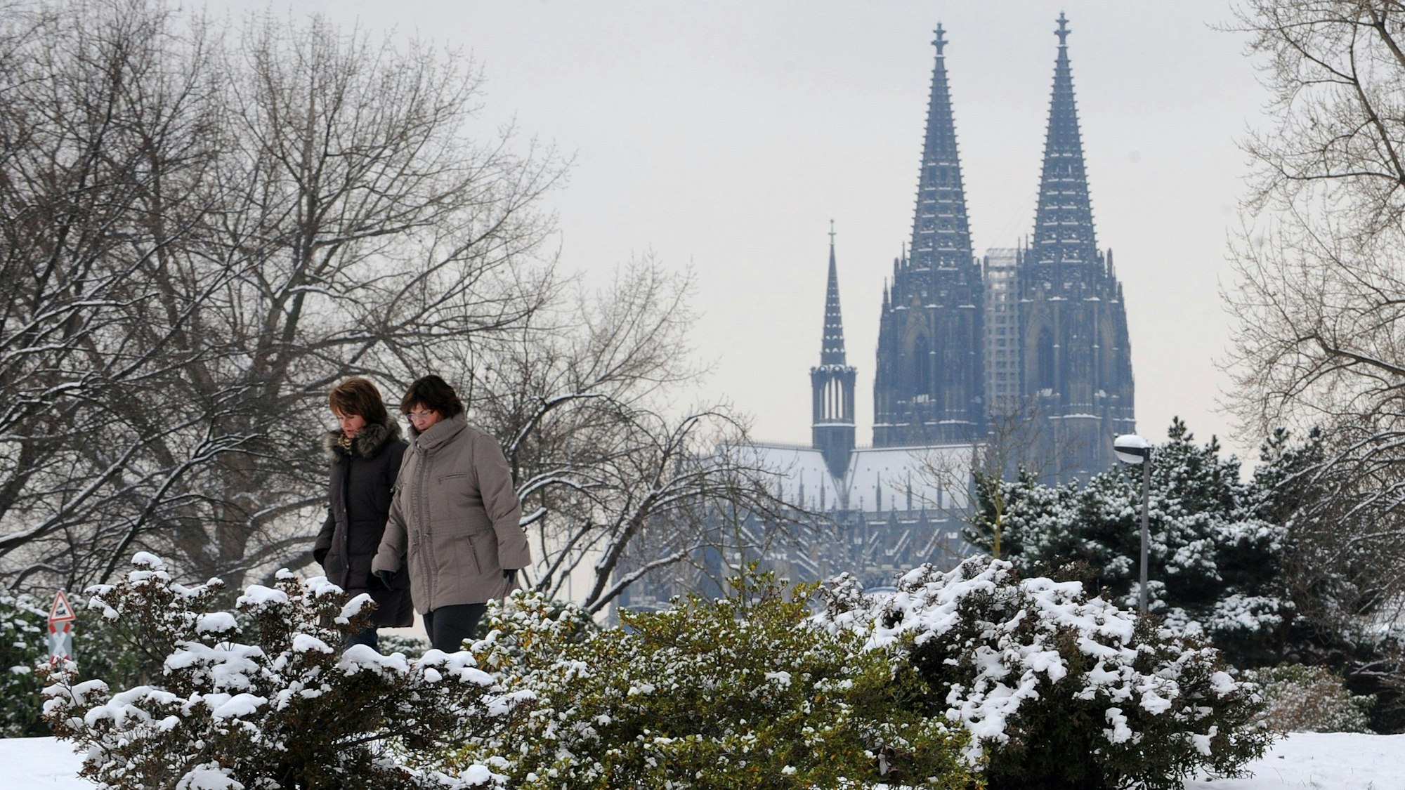 Zwei Frauen gehen am Dienstag (14.12.2010) durch den verschneiten Rheinpark in Köln.