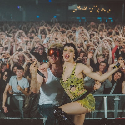 Die Sängerin Domiziana und der Rapper Ski Aggu, beide aus Berlin, posieren im April 2023 auf der Bühne des Kölner Popfestivals c/o pop vor gestikulierenden Fans.