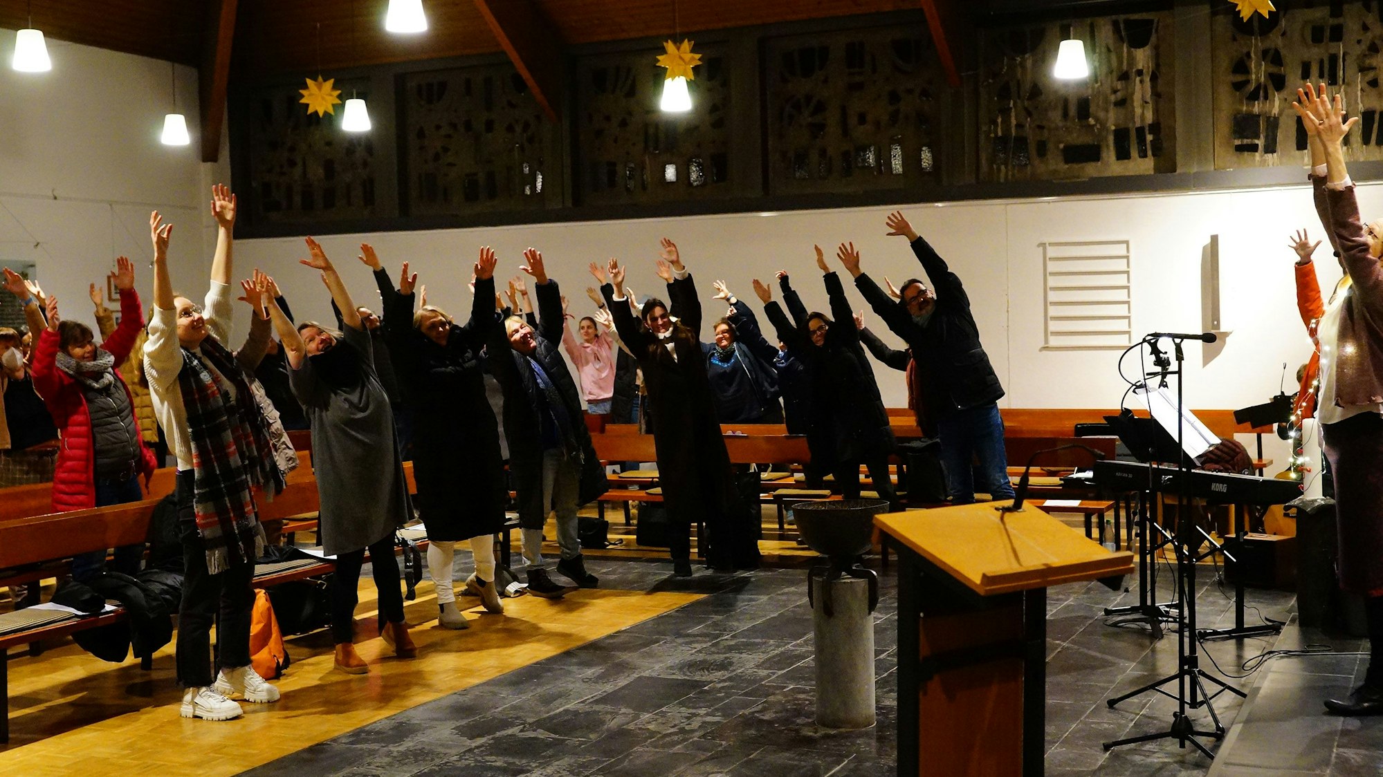 Sängerinnen und Sänger pendeln mal nach rechts, mal nach links, mit ausgestreckten Armen.