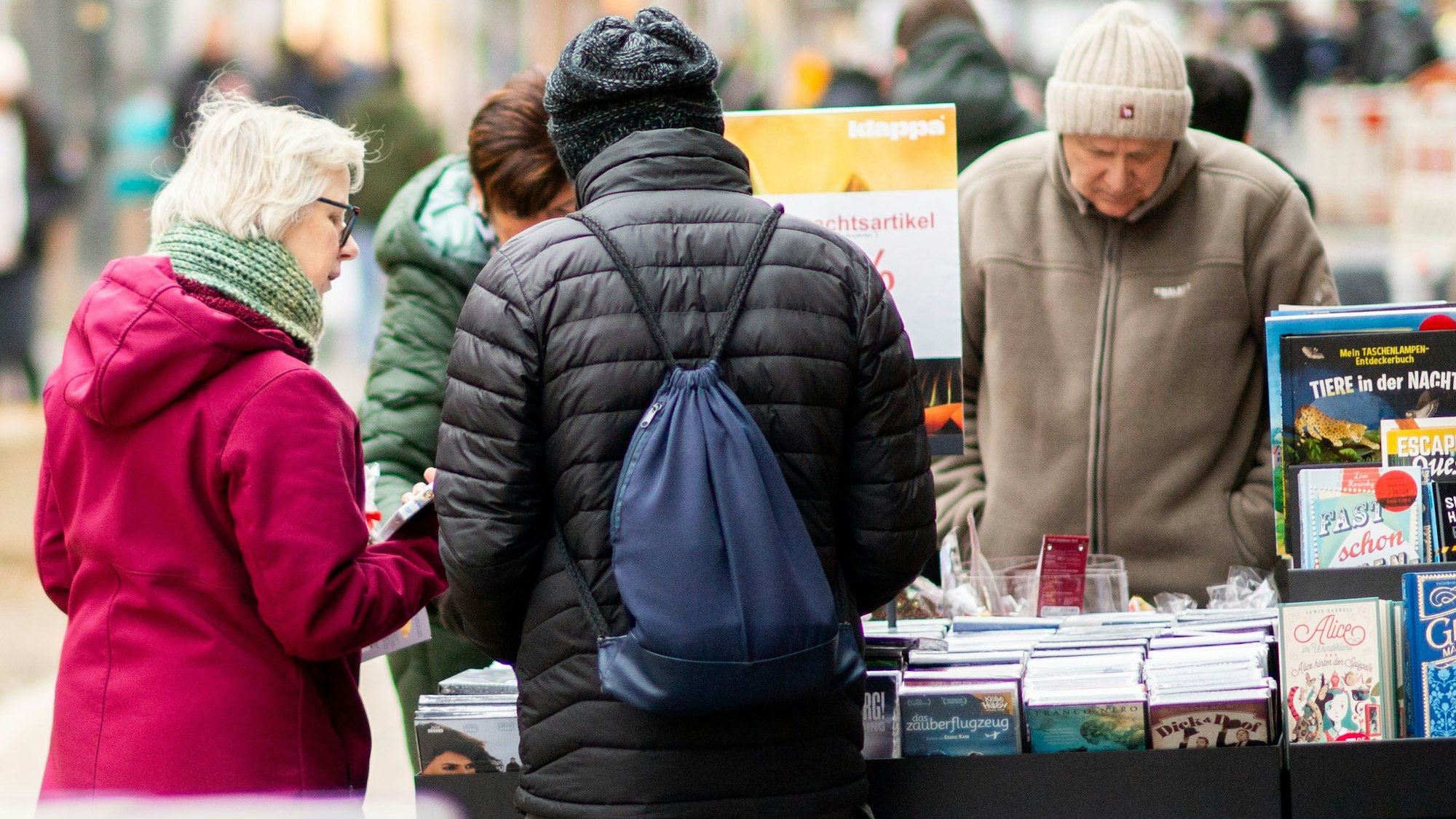 Das Bild zeigt mehrere potenzielle Kunden vor einem Wühltisch mit Büchern.