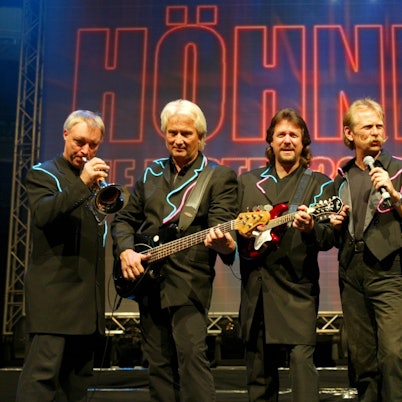 Peter Werner, Hannes Schöner, Pete Bauchwitz, Henning Krautmacher, Janus Fröhlich und Ralf Rudnik stehen im schwarzen Anzug auf einer Bühne.