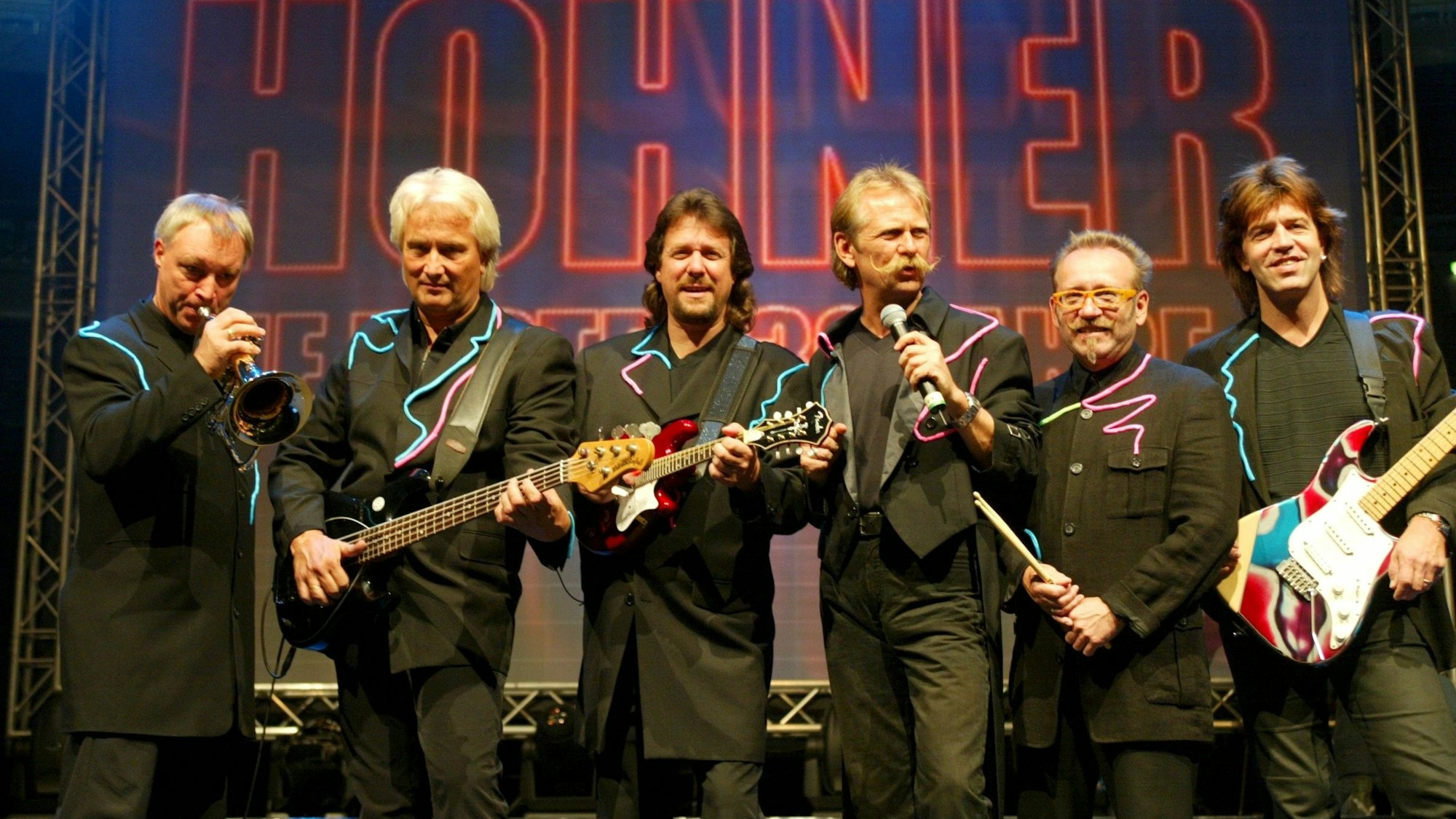 Peter Werner, Hannes Schöner, Pete Bauchwitz, Henning Krautmacher, Janus Fröhlich und Ralf Rudnik stehen im schwarzen Anzug auf einer Bühne.