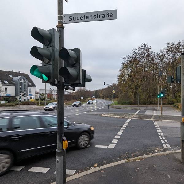 Eine Straßenkreuzung mit Ampel, ein Auto biegt nach rechs über die Fußgängerfurt ab.