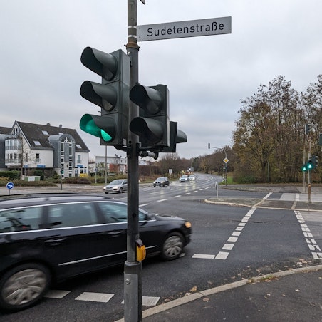 Eine Straßenkreuzung mit Ampel, ein Auto biegt nach rechs über die Fußgängerfurt ab.