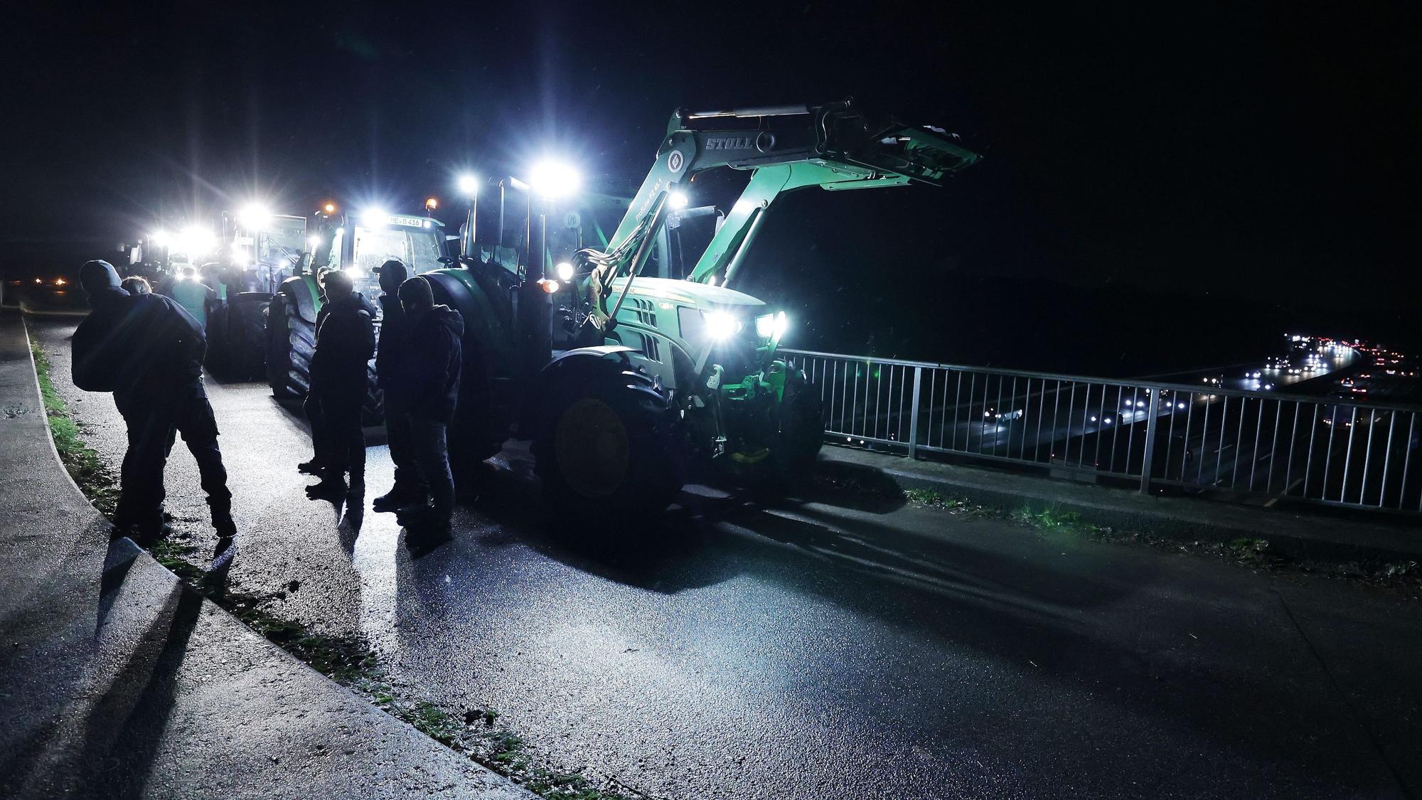 A3 bei Düsseldorf: Landwirte stehen mit Traktoren auf einer Brücke, um gegen die geplante Kürzung des Agrardiesels zu protestieren.