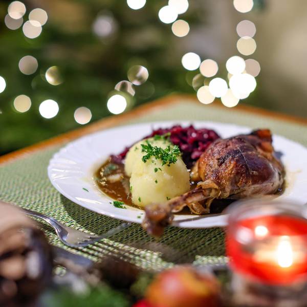 Eine Portion Gänsekeule mit Rotkraut und Klößen steht auf einem Tisch in einem Restaurant.