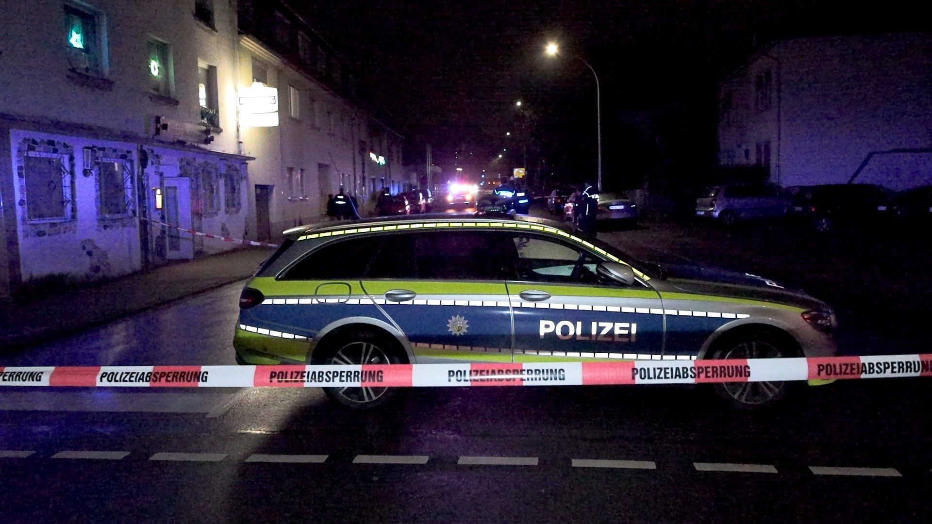 19.12.2023, Saarland, Neunkirchen: Einsatzkräfte der Polizei sind an einem mit Absperrband gesicherten Tatort vor einem Lokal im Einsatzt. Vor einer Kneipe im saarländischen Neunkirchen sind am Dienstagabend Schüsse gefallen. Ein 53-jähriger Mann wurde durch einen Schuss am Bein verletzt, wie ein Sprecher der Polizei sagte. Es habe vor dem Lokal zwei Schüsse gegeben. Der Täter war den Angaben zufolge zunächst flüchtig. Nach ihm wurde am Abend gefahndet Foto: Thorsten Kremers/dpa +++ dpa-Bildfunk +++