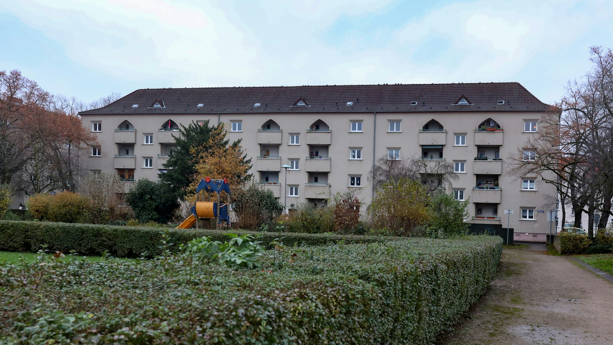 Mehrfamilienwohnhaus, vor dem sich eine Grünfläche und ein Spielplatz befinden