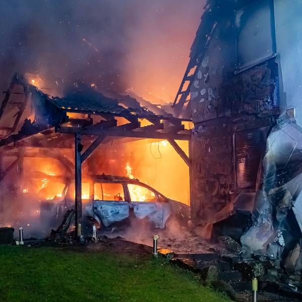Ein Carport steht in Vollband, ein angrenzendes Haus ist ebenfalls sichtbar Opfer der Flammen geworden.