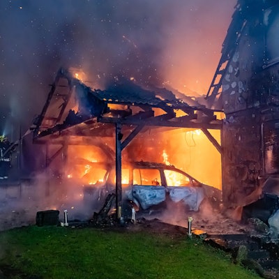 Ein Carport steht in Vollband, ein angrenzendes Haus ist ebenfalls sichtbar Opfer der Flammen geworden.