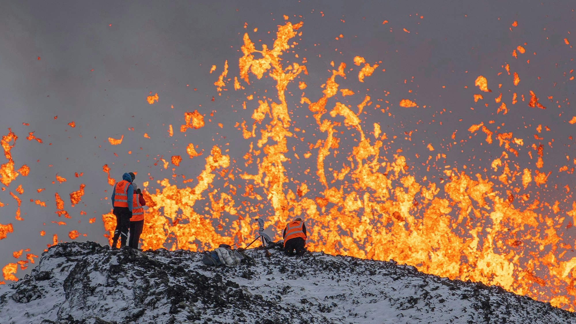 Wissenschaftler der Universität von Island nehmen Messungen und Proben, während sie auf dem Kamm vor dem aktiven Teil der Eruptionsspalte eines aktiven Vulkans in Grindavik auf der isländischen Halbinsel Reykjanes stehen.
