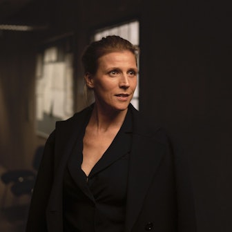 Julia Grosz steht im dunklen Flur eines Büros. Sie trägt schwarze Kleidung.