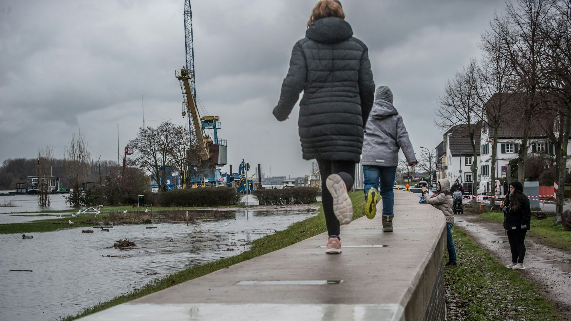 Kinder laufen am Rhein in Hitdorf entlang.