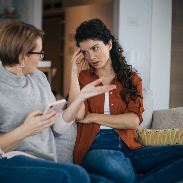 Junge Frau streitet auf dem Sofa mit ihrer Mutter.