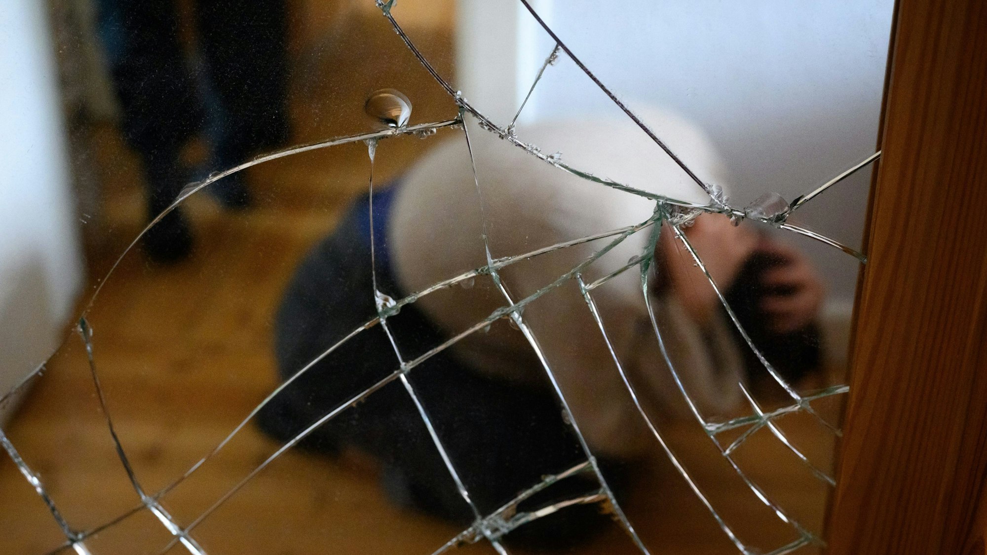Ein Mann steht neben einer am Boden kauernden Frau die sich mit ihren Händen am Kopf schützt (gestellte Szene).