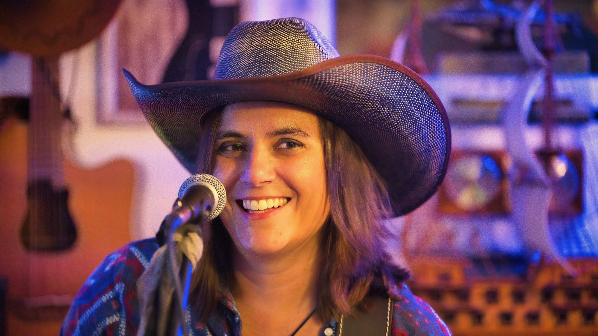 Eine Frau mit Cowboyhut vor einem Mikrofon