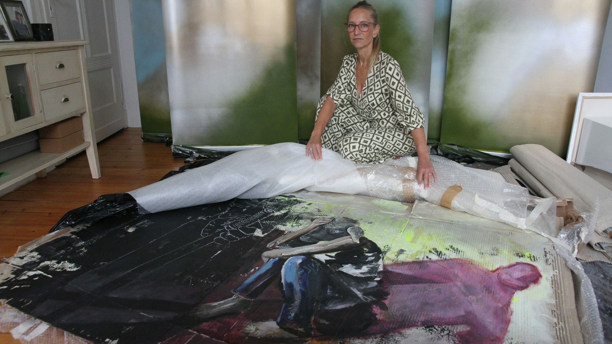 Eine Malerin breitet ein Bild auf dem Boden aus