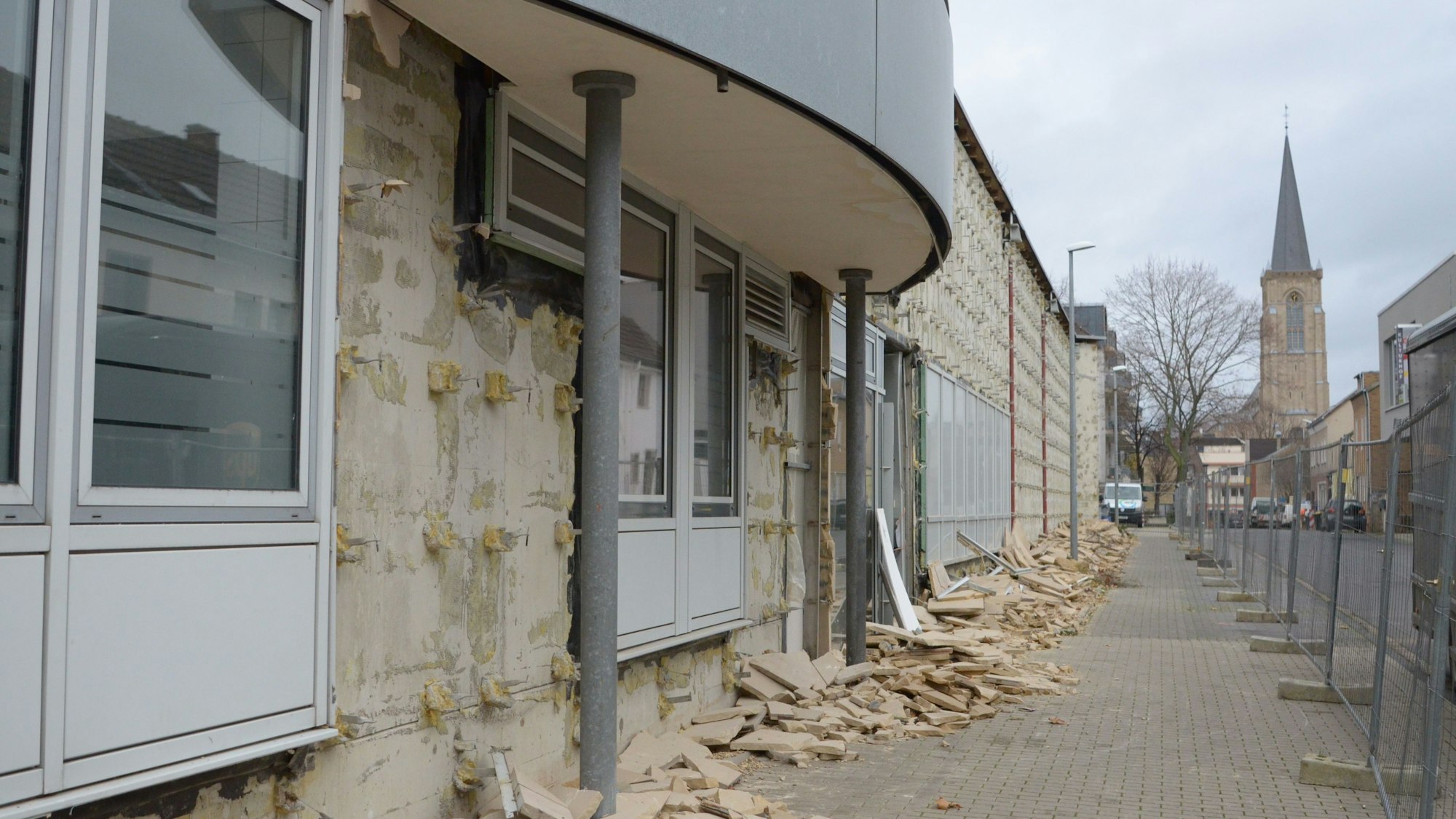 Ein Blick vom Neutorwall auf das City-Forum. Am Rand des Grundstücks steht ein Bauzaun, im Hintergrund die Herz-Jesu-Kirche.
