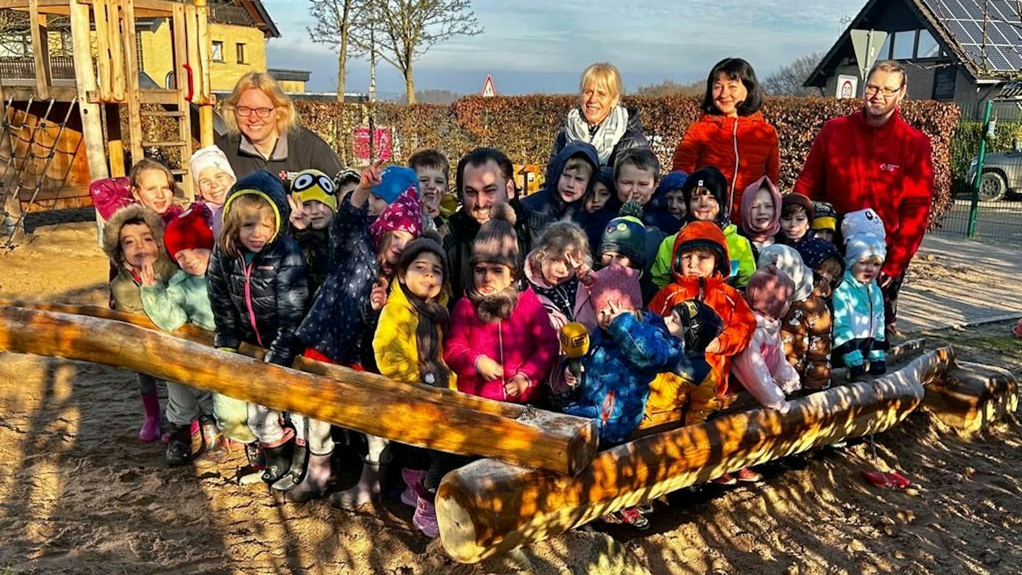 Kinder stehen mit Erzieherinnen auf dem Außengelände der DRK-Kita Birken in Overath-Heiligenhaus.