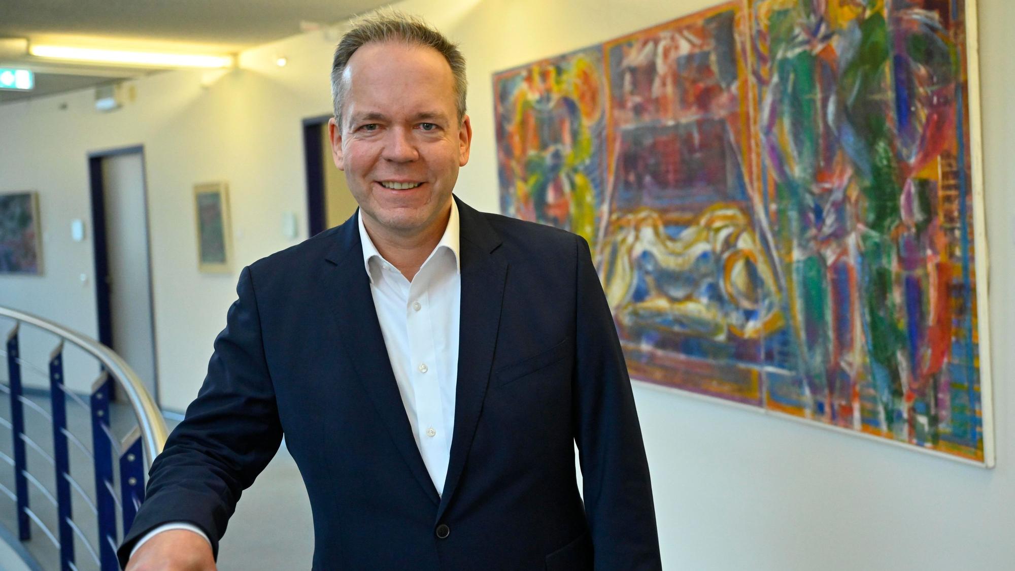Klaus Grootens vor einem bunten Gemälde im Gummersbacher Kreishaus.