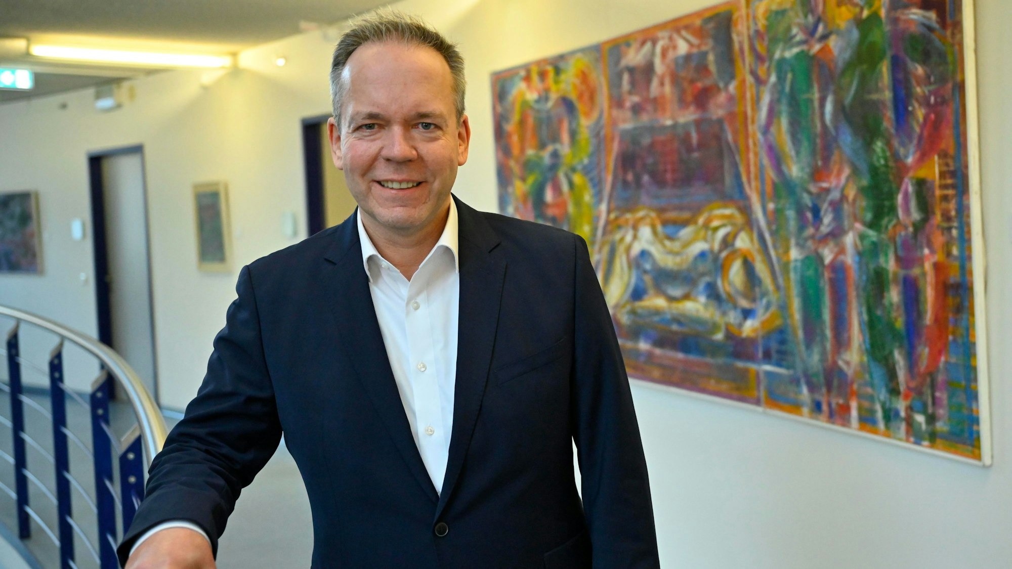 Klaus Grootens vor einem bunten Gemälde im Gummersbacher Kreishaus.