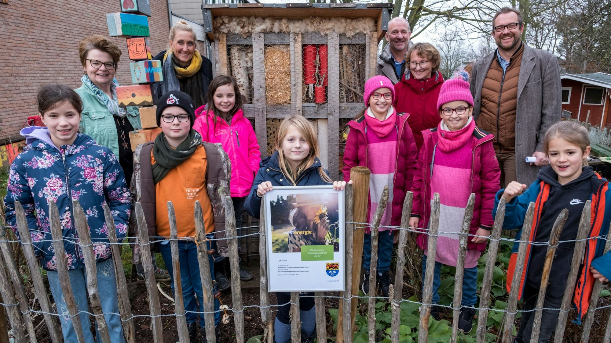 Kinder und Erwachsene stehen vor dem Insektenhotel der Grundschule in Lückerath.