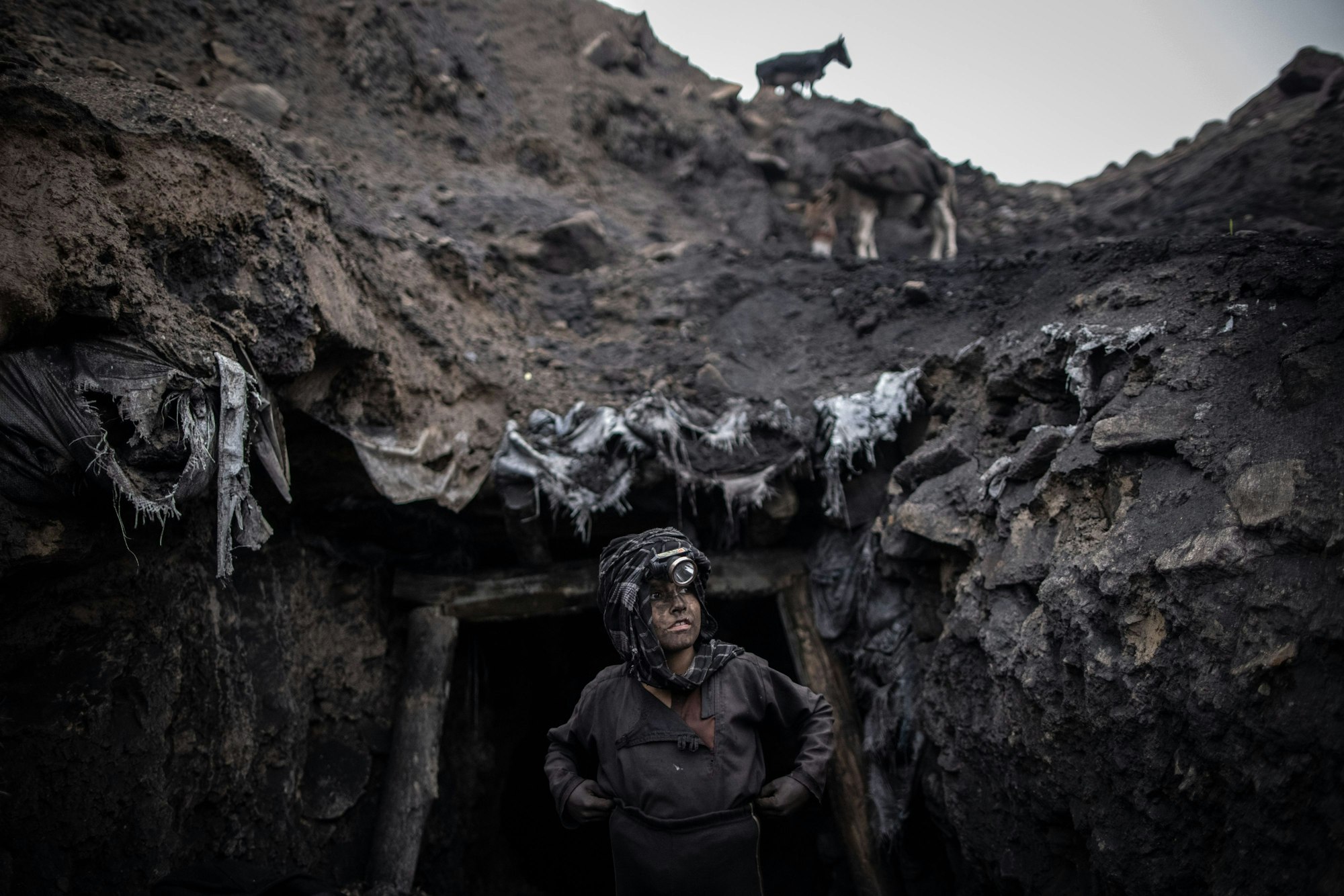 Das Foto zeigt einen Jungen, der als Bergarbeiter arbeitet, steht vor einem informellen Kohlebergwerk in Chinarak in der afghanischen Provinz Baghlan.