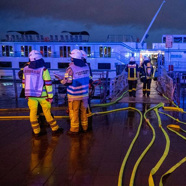 Feuerwehrleute stehen an dem Schiff.