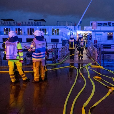 Feuerwehrleute stehen an dem Schiff.