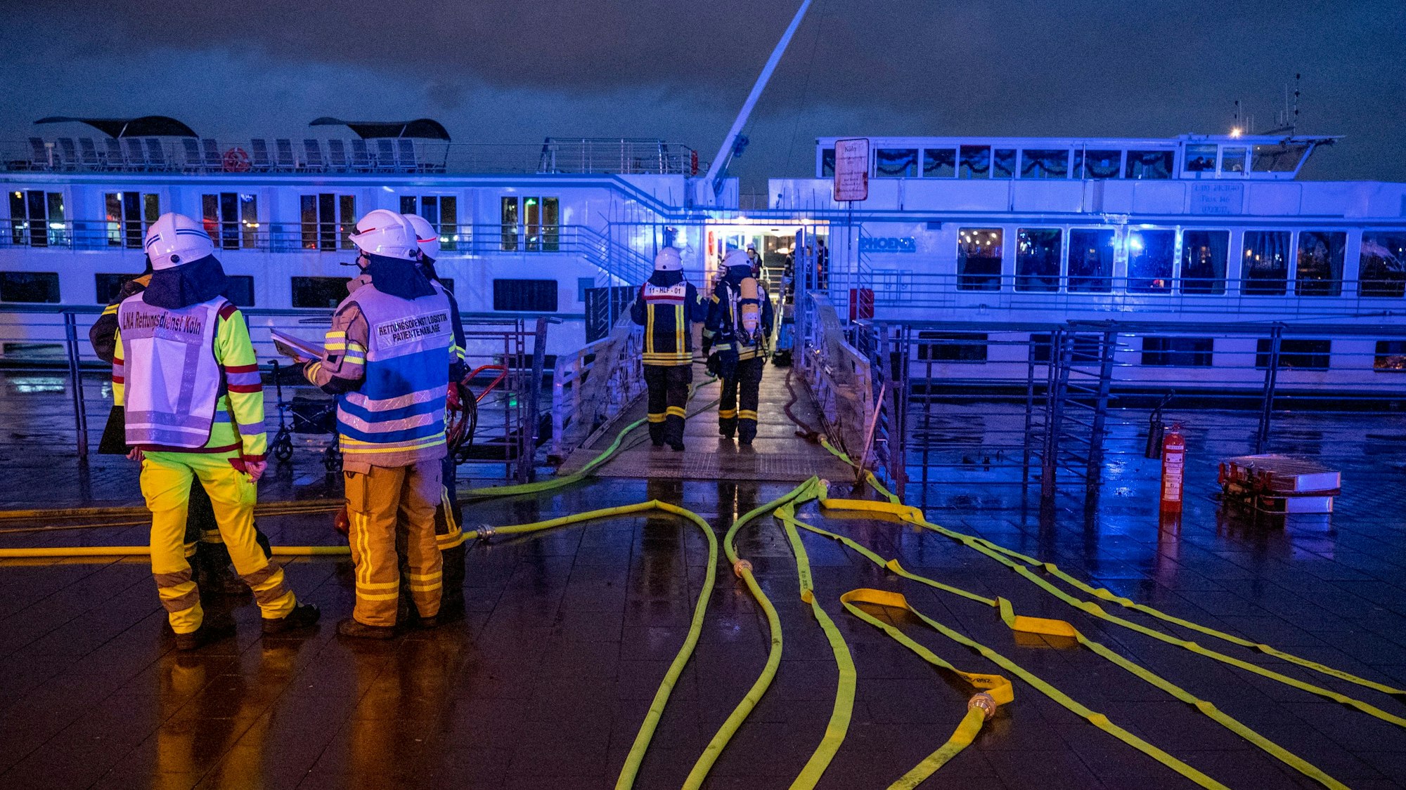 Feuerwehrleute stehen an dem Schiff.