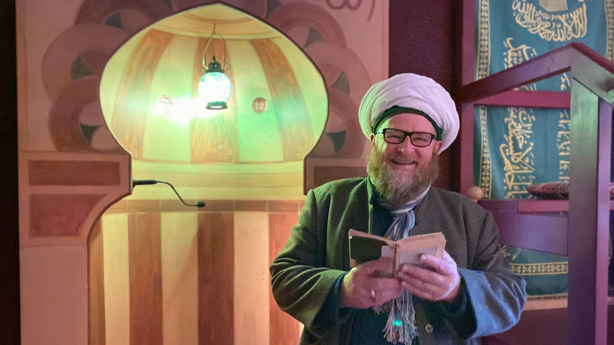 Ahmad Adamek trägt Gebetsmütze und Turban. Er liest in der osmanischen Herberge in Kall-Sötenich aus dem Koran.