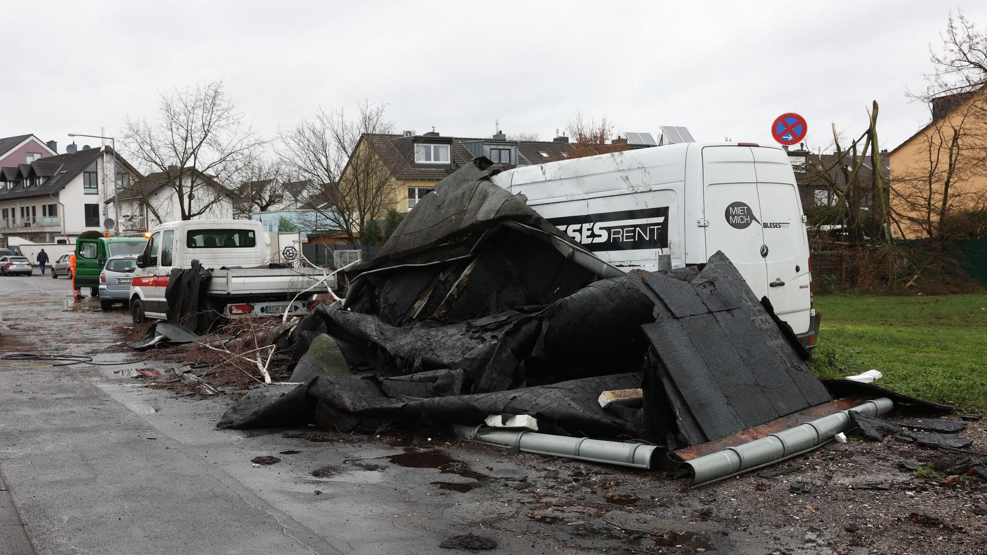Ein abgedecktes Dach ist auf eine Straße in Köln-Poll geweht worden und liegt vor einem Kleintransporter.